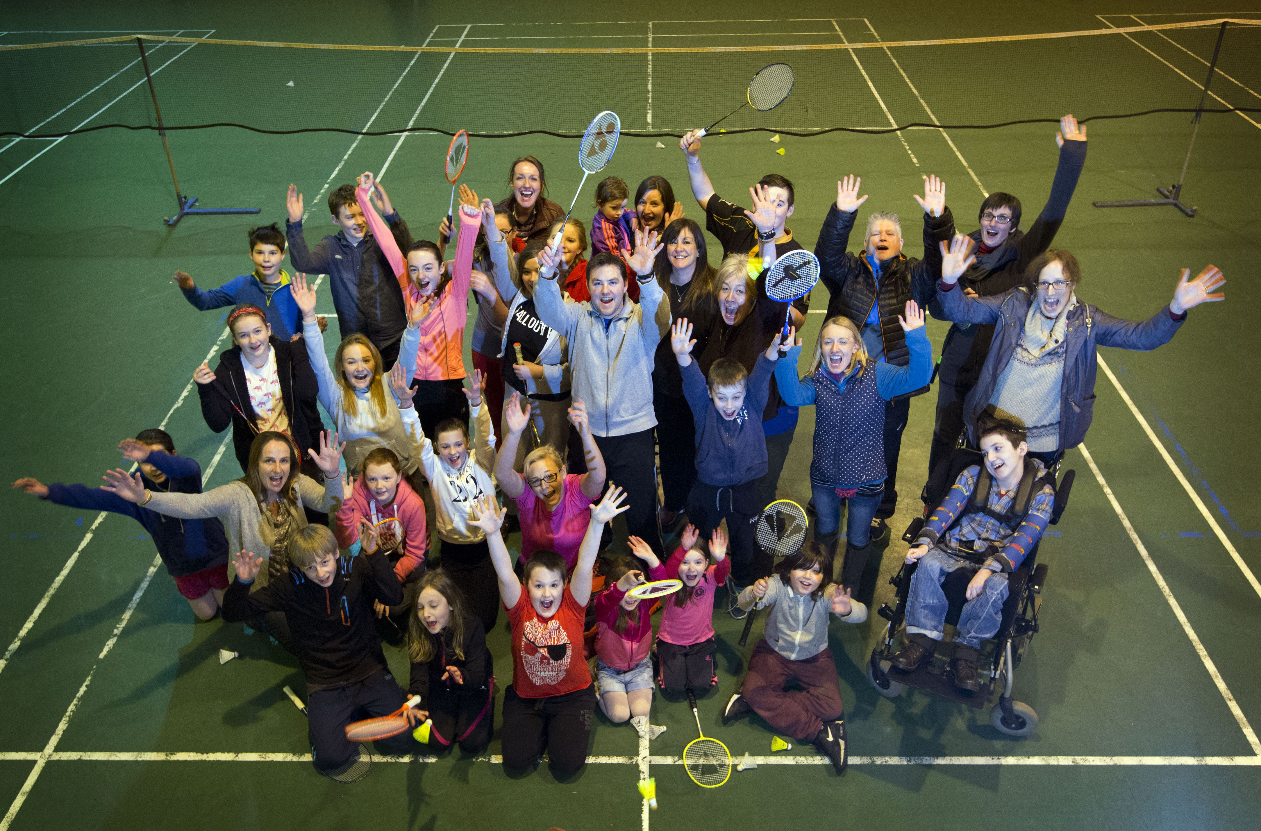 Group of people in a community hall celebrating with arms in the air