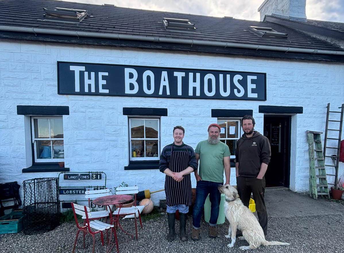 3 employees and their dog standing in front of the white stone boat house